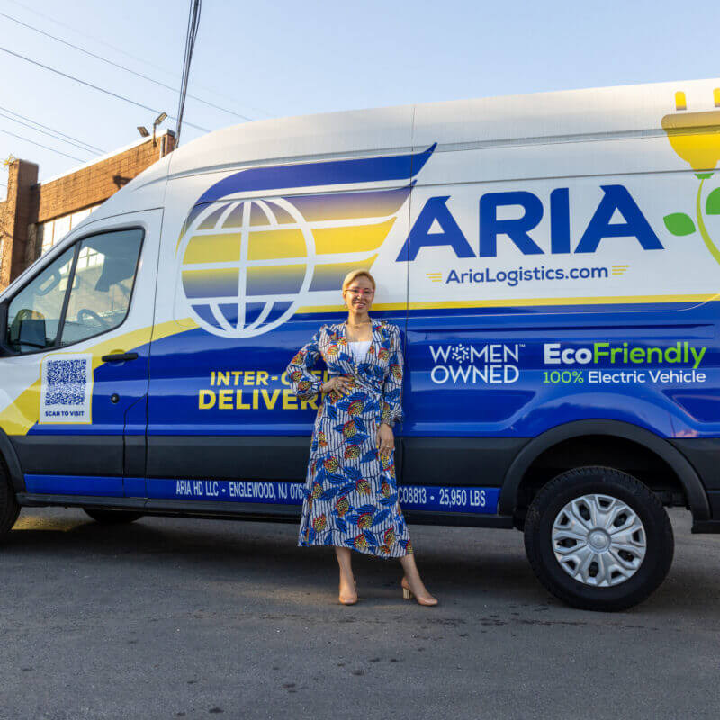Aria Logistics founder standing in front of a women-owned eco-friendly 100% electric delivery van