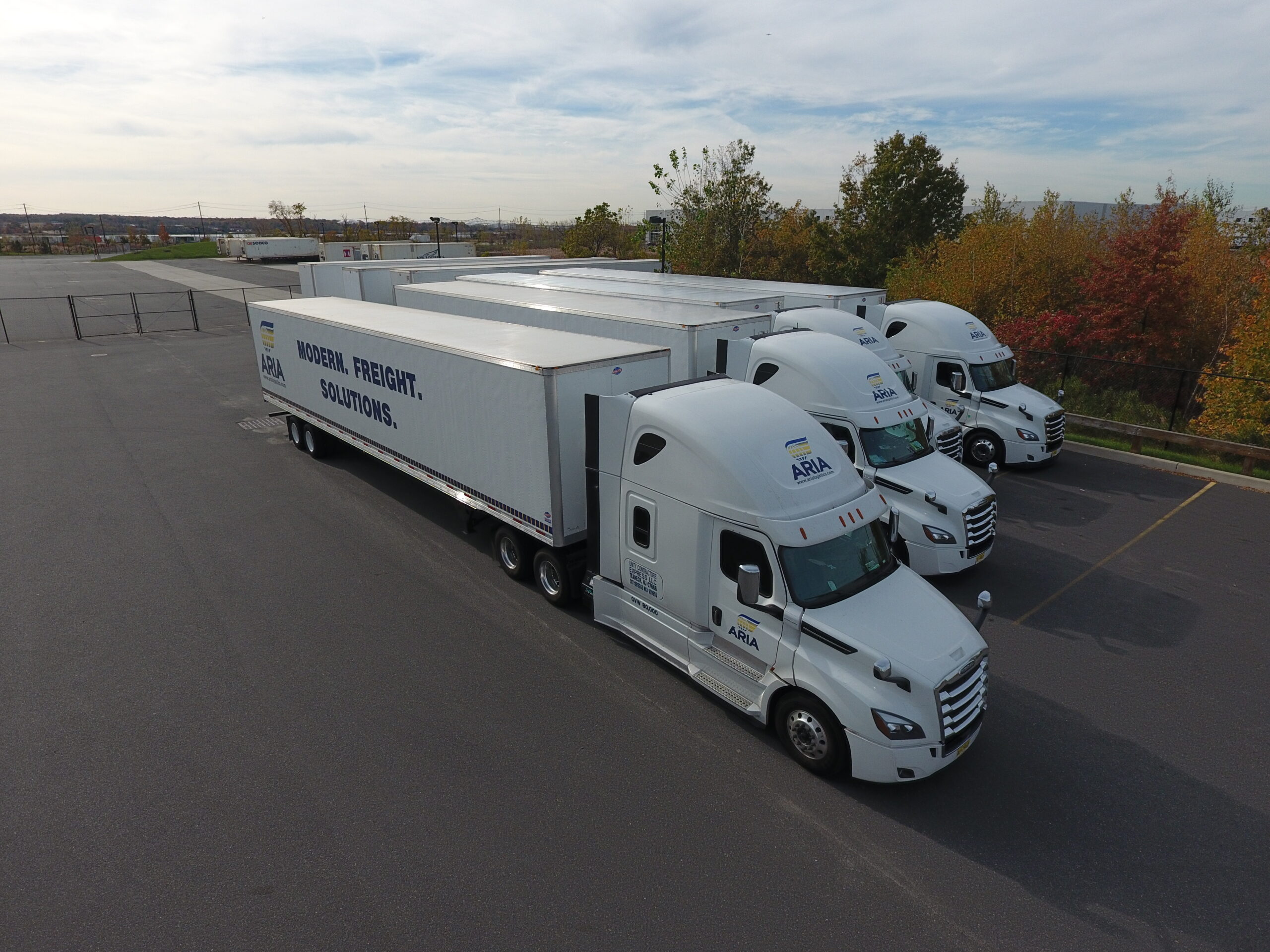Aria Logistics fleet of white semi trucks parked in a lot with Modern Freight Solutions branding